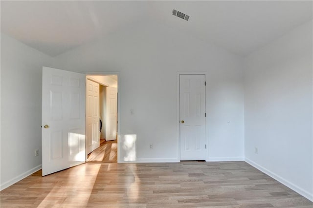 spare room with vaulted ceiling and light wood-type flooring