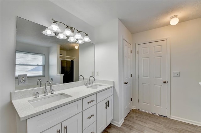 bathroom with hardwood / wood-style floors, vanity, and a shower with shower door