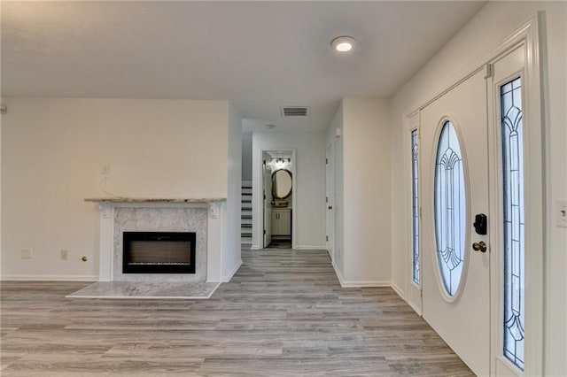 foyer entrance with a fireplace and light hardwood / wood-style flooring