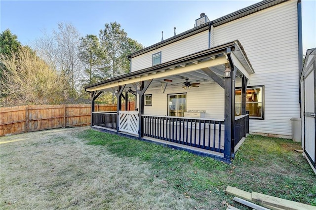 back of house with ceiling fan and a yard