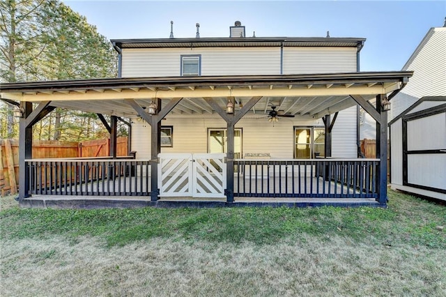 rear view of house with ceiling fan, a yard, and a storage unit