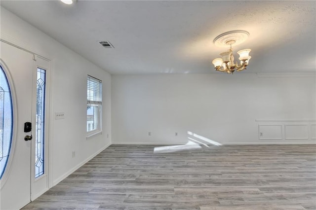 foyer entrance featuring light wood-type flooring and a chandelier