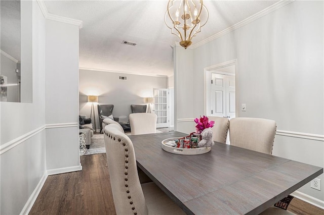 dining room featuring wood finished floors, baseboards, crown molding, and a chandelier