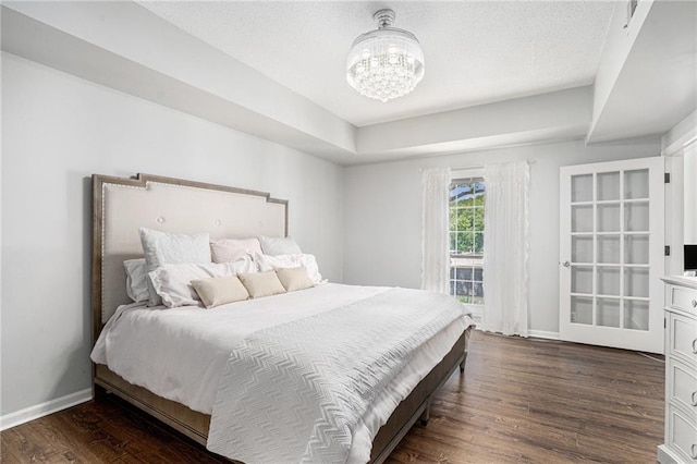 bedroom with dark wood-style floors, baseboards, and a chandelier