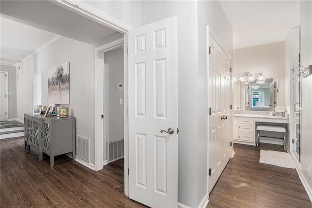 hallway with dark wood-type flooring, crown molding, and baseboards