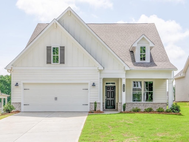 view of front of home featuring board and batten siding, roof with shingles, a front yard, driveway, and stone siding