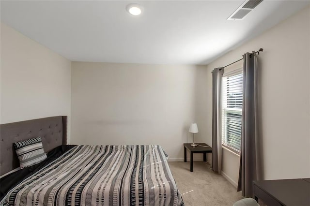 bedroom featuring visible vents, light colored carpet, and baseboards