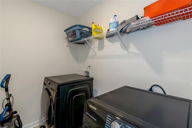 washroom featuring laundry area, washing machine and clothes dryer, and baseboards