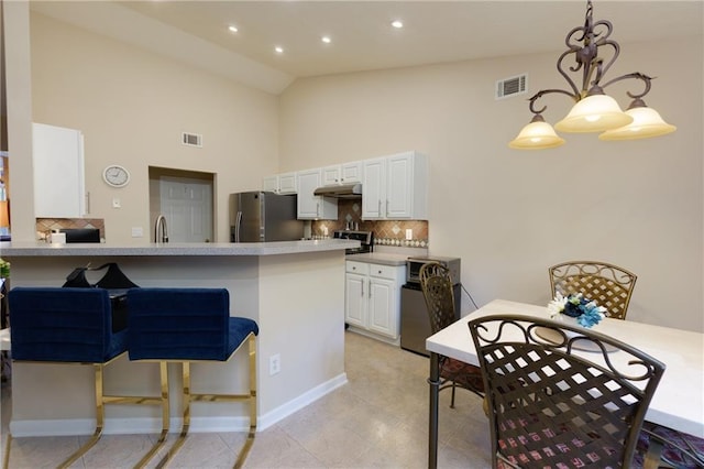 kitchen with under cabinet range hood, visible vents, white cabinetry, and stainless steel refrigerator with ice dispenser