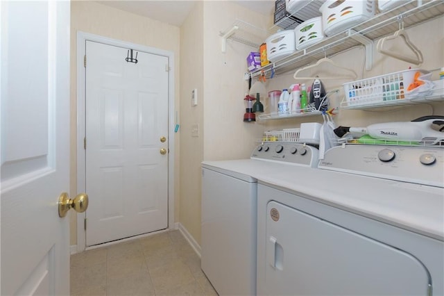 laundry room featuring laundry area, light tile patterned flooring, washing machine and dryer, and baseboards