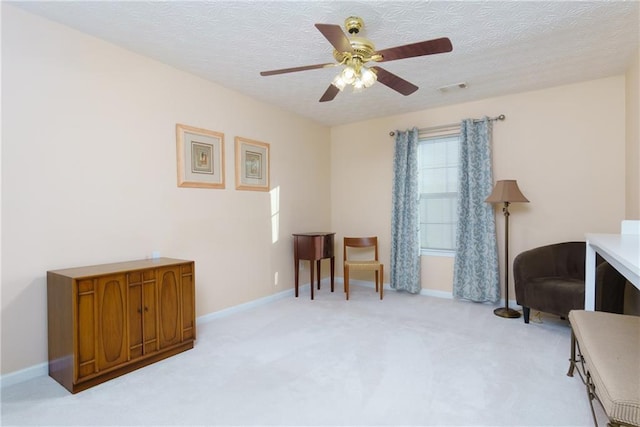 living area featuring baseboards, light colored carpet, visible vents, and a textured ceiling