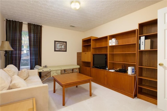 living room with visible vents, light colored carpet, and a textured ceiling