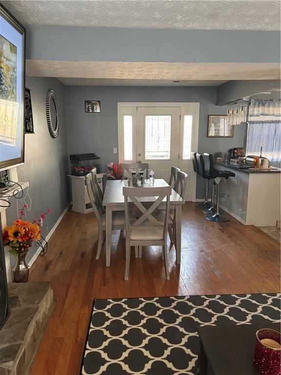 dining area with dark wood-style floors, a textured ceiling, and baseboards