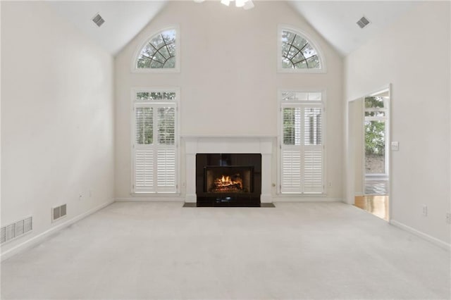 unfurnished living room with carpet flooring, visible vents, and a fireplace with flush hearth