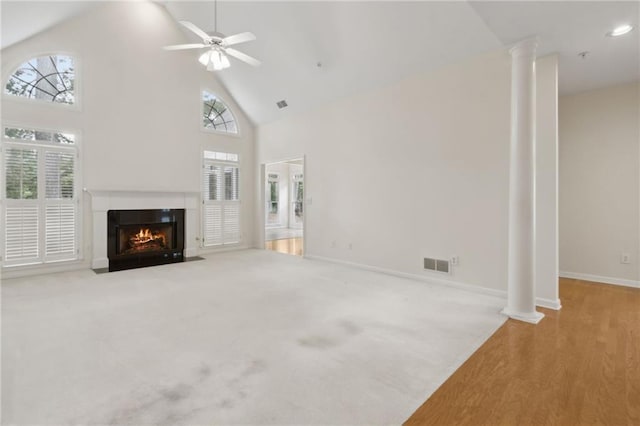 unfurnished living room with a fireplace with flush hearth, high vaulted ceiling, decorative columns, and visible vents