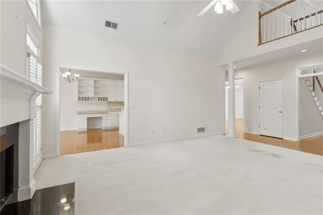 unfurnished living room with visible vents, a fireplace with flush hearth, ceiling fan with notable chandelier, and high vaulted ceiling