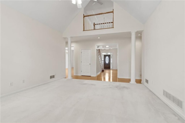 carpeted spare room with high vaulted ceiling, decorative columns, and visible vents