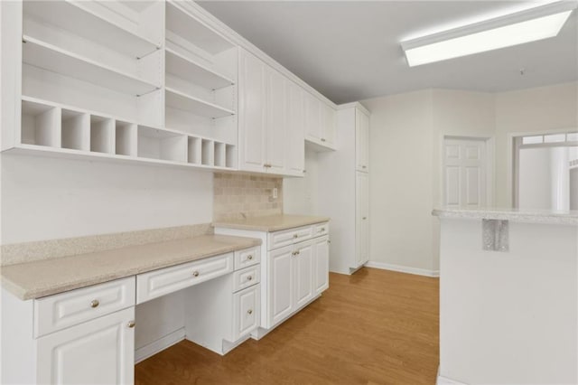 kitchen featuring tasteful backsplash, open shelves, light countertops, white cabinets, and light wood-style floors
