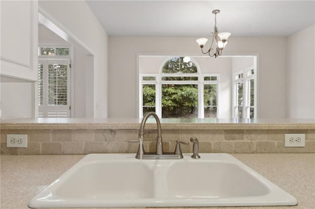 details with a sink, light countertops, hanging light fixtures, and a notable chandelier