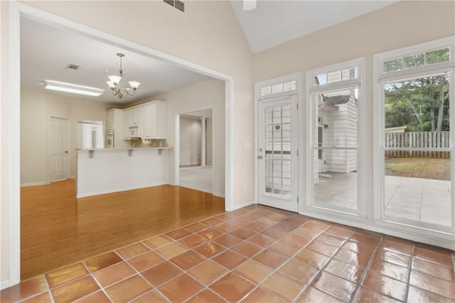 doorway to outside with an inviting chandelier, baseboards, lofted ceiling, and visible vents