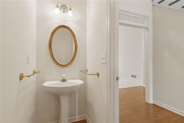 bathroom with baseboards, visible vents, and wood finished floors