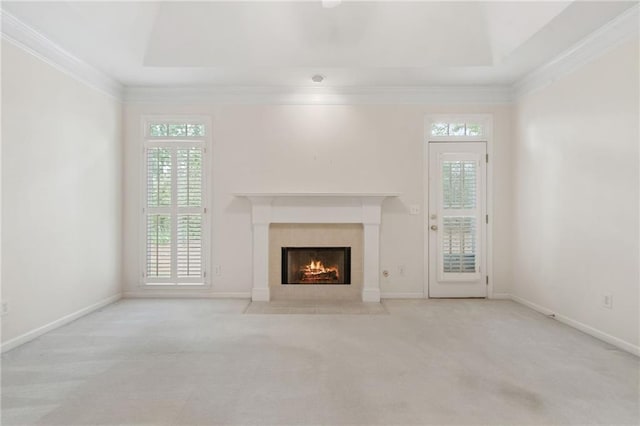 unfurnished living room featuring a tray ceiling, a fireplace with flush hearth, and a healthy amount of sunlight