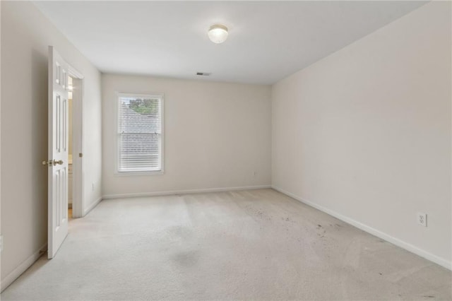 unfurnished room with baseboards, light colored carpet, and visible vents