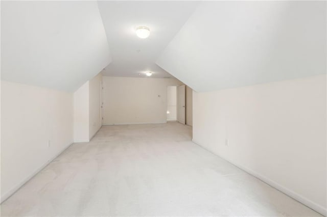 additional living space featuring light colored carpet, baseboards, and lofted ceiling