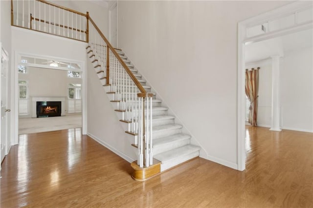 stairs with baseboards, a high ceiling, and wood finished floors