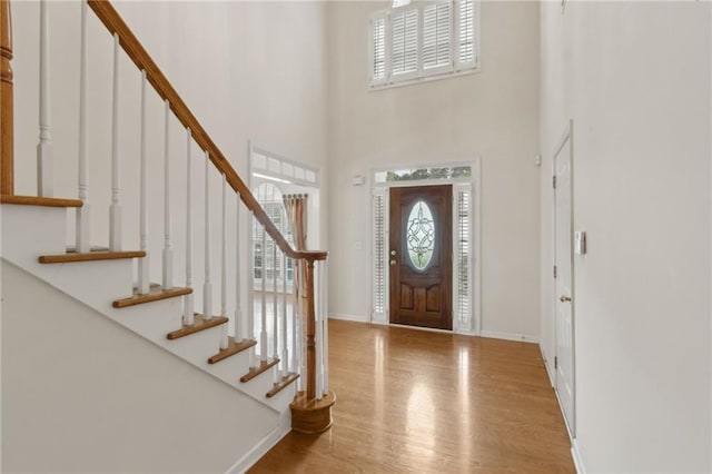 foyer featuring baseboards, stairs, wood finished floors, and a towering ceiling