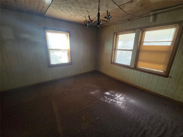 carpeted spare room with a chandelier