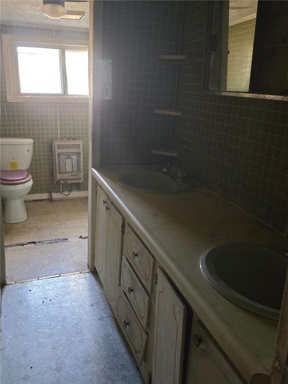 bathroom featuring vanity, toilet, tile walls, and heating unit