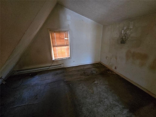 additional living space featuring baseboard heating, a textured ceiling, and vaulted ceiling