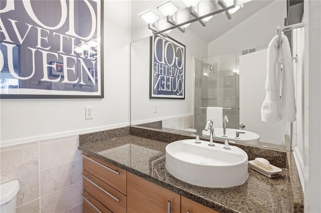 bathroom featuring a stall shower, vaulted ceiling, vanity, and tile walls