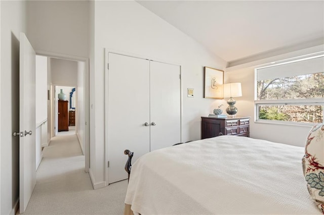 bedroom with vaulted ceiling, a closet, and light colored carpet