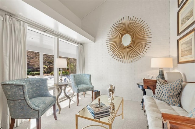 carpeted living area with brick wall