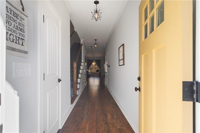 hall featuring dark wood-type flooring and an inviting chandelier