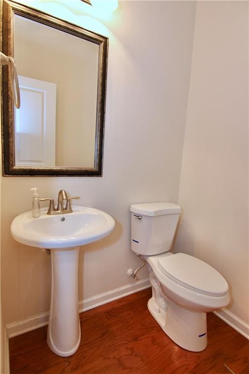 half bathroom with toilet, baseboards, and wood finished floors