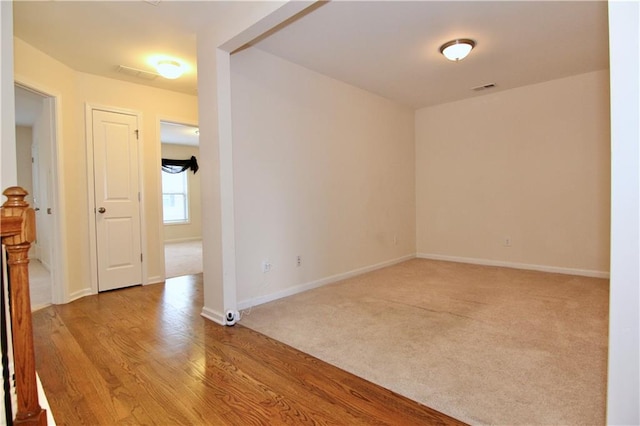 empty room with visible vents, baseboards, wood finished floors, and carpet flooring