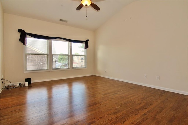 empty room featuring a ceiling fan, wood finished floors, visible vents, baseboards, and vaulted ceiling