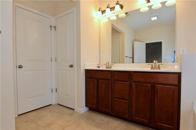 full bath with double vanity, vaulted ceiling, tile patterned floors, and a sink