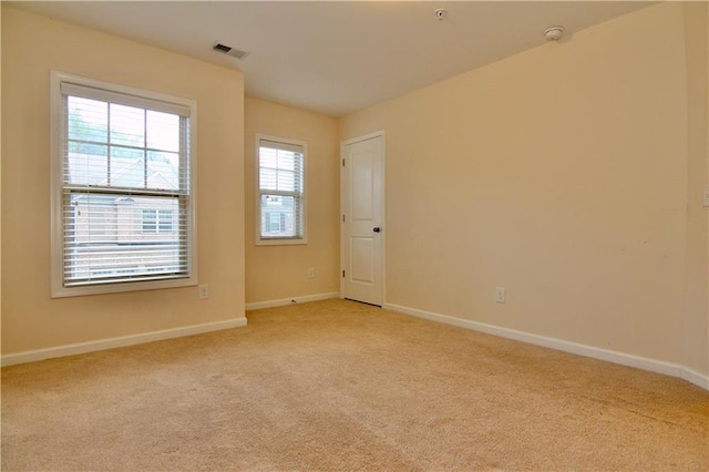 empty room with visible vents, light colored carpet, and baseboards