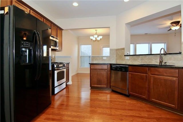 kitchen with a sink, stainless steel appliances, light wood-style flooring, and decorative backsplash