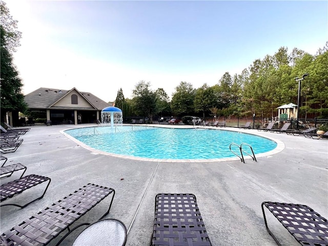 pool featuring a patio, fence, and playground community