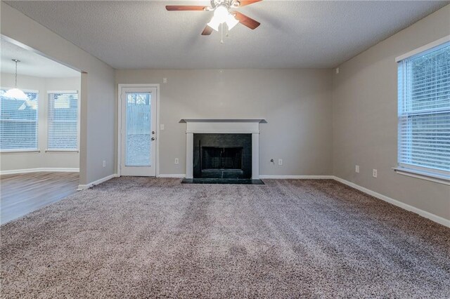 unfurnished living room featuring carpet flooring, ceiling fan, and a textured ceiling