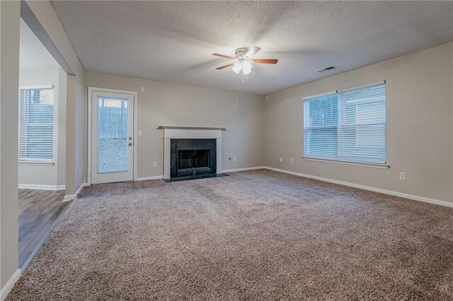 unfurnished living room with ceiling fan, carpet floors, and a textured ceiling