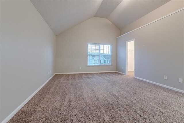 carpeted empty room with vaulted ceiling