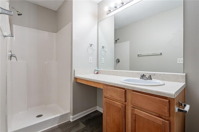 bathroom featuring hardwood / wood-style floors, vanity, and a shower