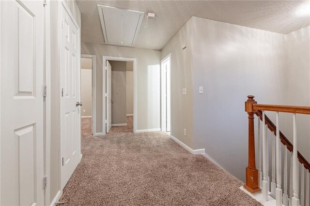 hallway with a textured ceiling and light colored carpet