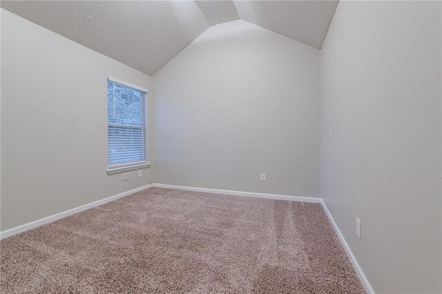 spare room with a textured ceiling, carpet floors, and vaulted ceiling